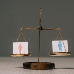 male and female symbols on scales on wooden table on grey, gender equality concept