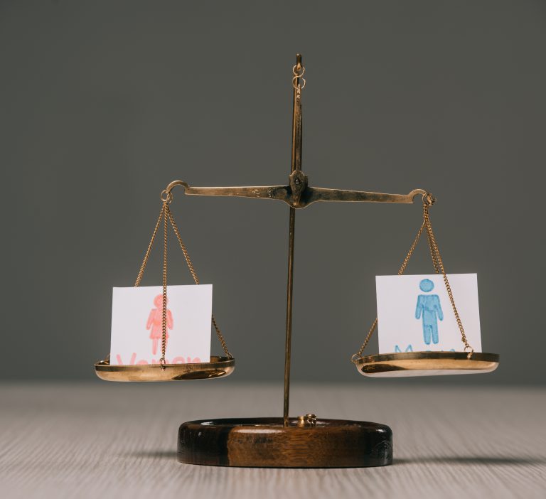 male and female symbols on scales on wooden table on grey, gender equality concept